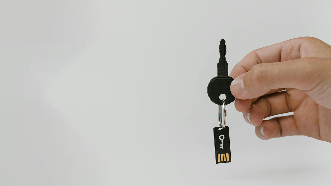 Hands Holding a key with a U S B keychain to represent cybersecurity